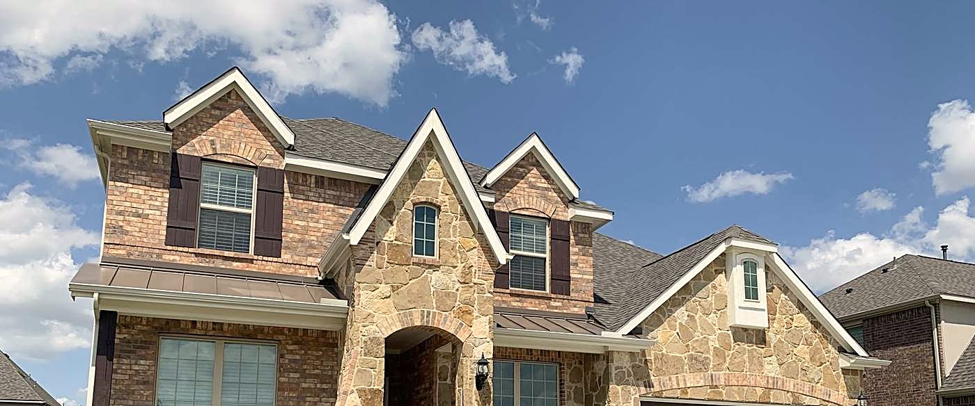 A two-story brick and stone home with a new asphalt shingle roof