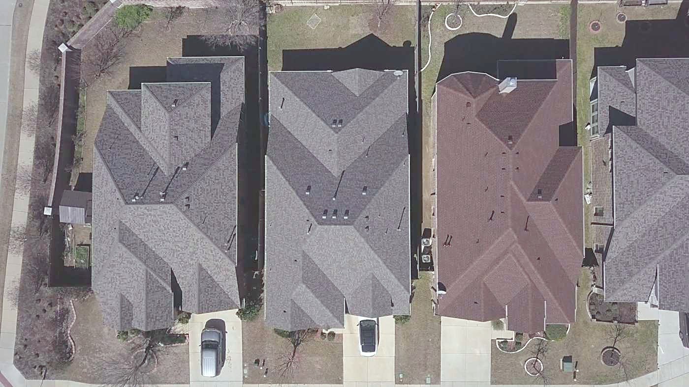 Overhead drone view of three finished roofs on a residential street in Frisco, Texas