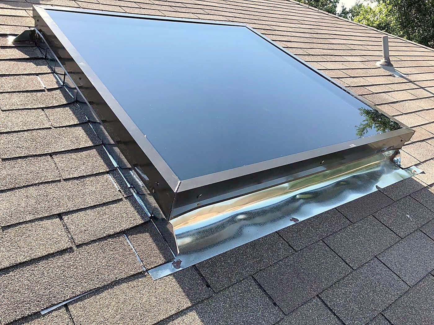 New metal flashing around a skylight on an asphalt shingle roof